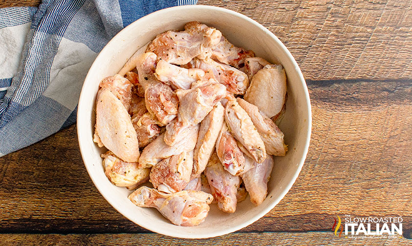 adding seasoning to chicken wings