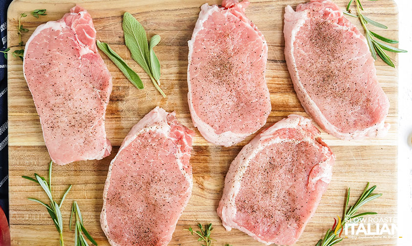 seasoned pork chops on wooden cutting board