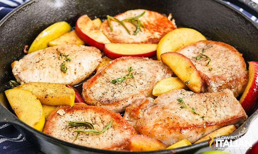 seasoned pork chops and apple slices in cast iron pan