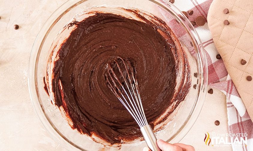 whisking brownie batter in glass bowl
