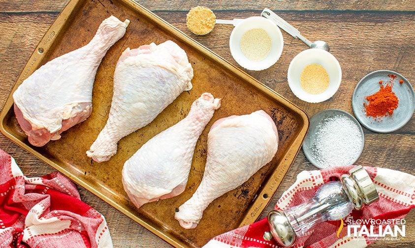 uncooked turkey legs on sheet pan with seasonings