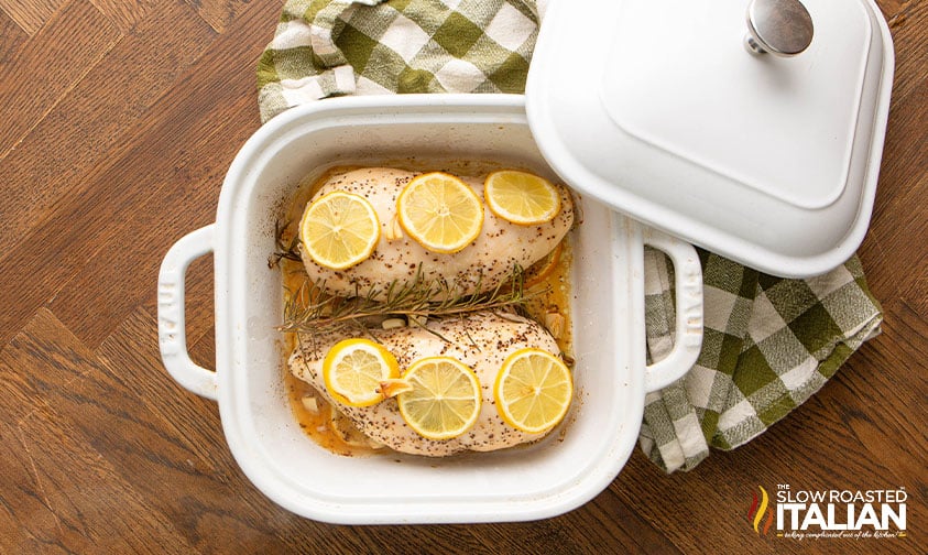 Chicken breasts in a casserole dish with rosemary and lemon slices