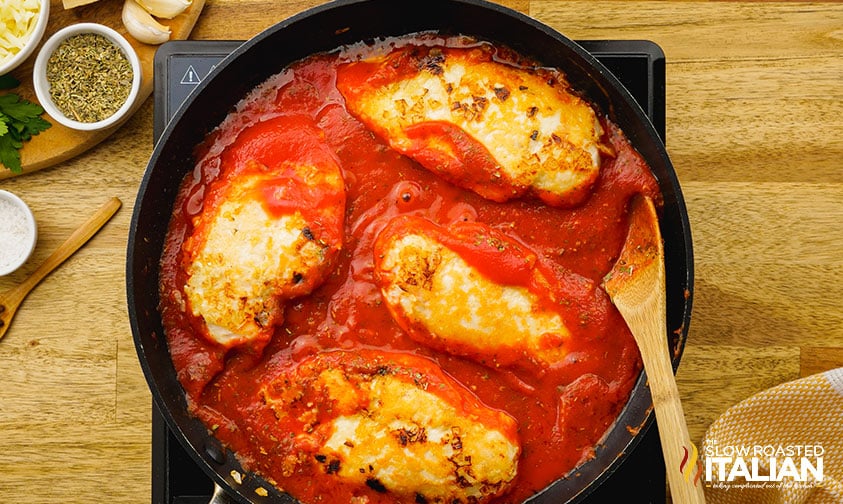 chicken breasts simmering in tomato sauce