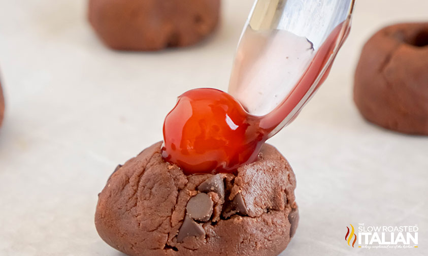 adding cherry to the center of chocolate thumbprint cookie dough
