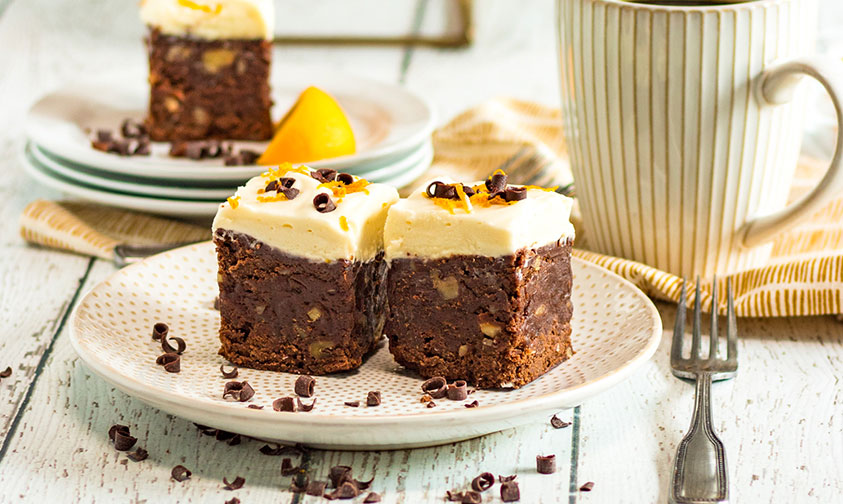 2 fudgy orange brownies on a plate with a fork.