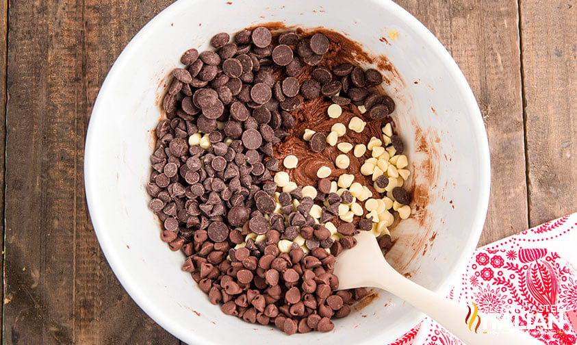 adding chocolate chips to cookie dough