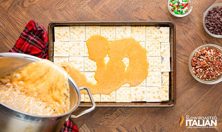 pouring homemade caramel sauce over crackers in baking sheet
