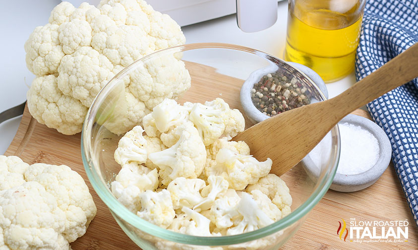 seasoning cauliflower in a mixing bowl