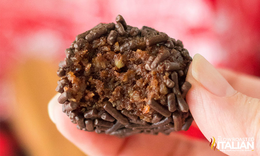 fingers holding boozy rum ball with sprinkles