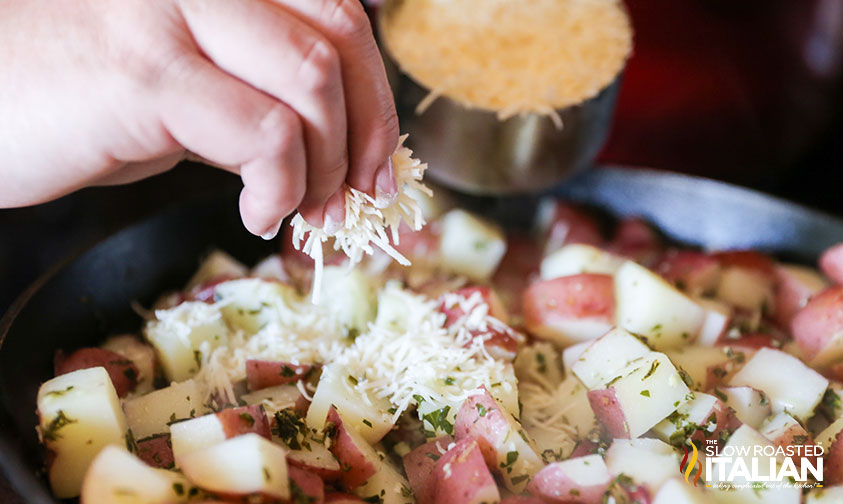 adding parmesan cheese to potatoes in a skillet