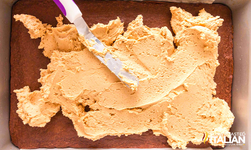 spreading peanut butter filling to brownies in baking pan