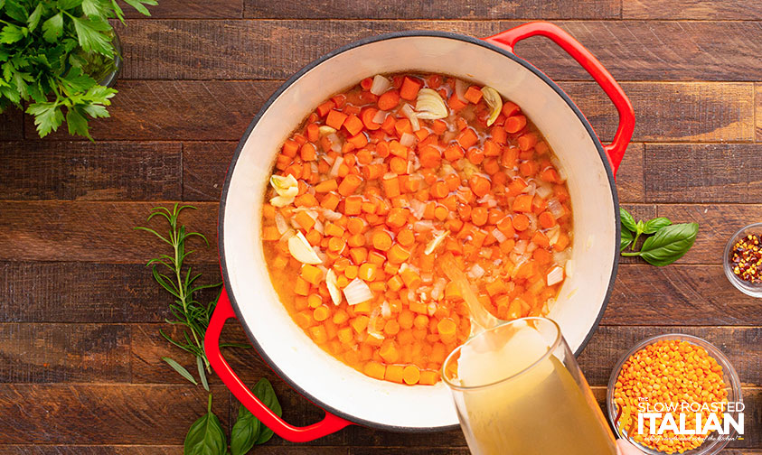 adding carrots and broth to pot