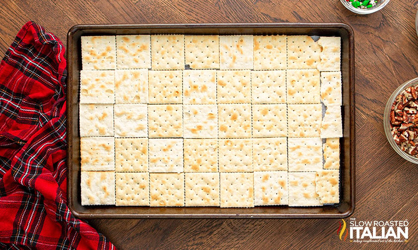 saltine crackers lined on a baking sheets