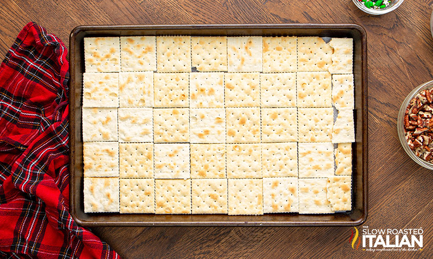 saltine crackers lined on a baking sheets