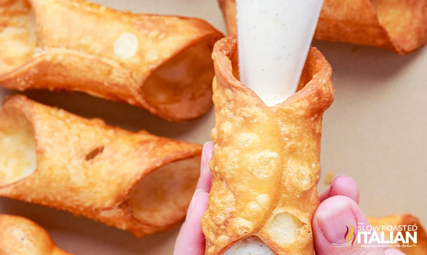 piping cannoli cream into cannoli shells