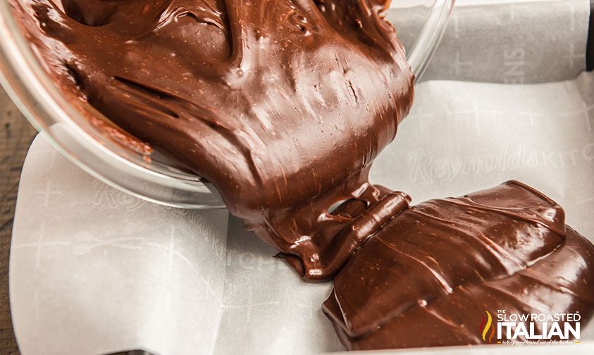 pouring melted chocolate mixture into parchment lined pan