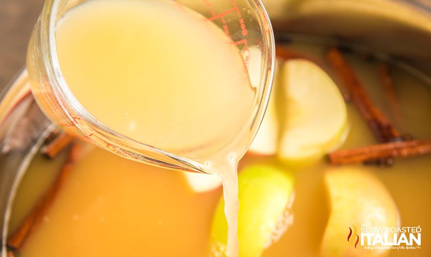 pouring pineapple juice into pot of apple cider