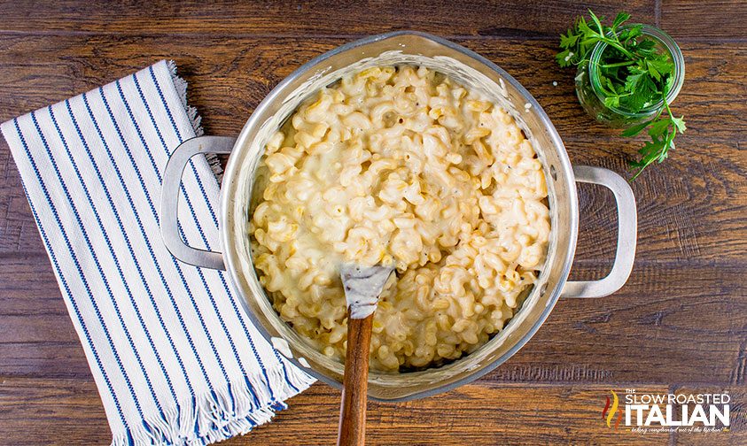 stirring macaroni noodles into pot of cheese sauce