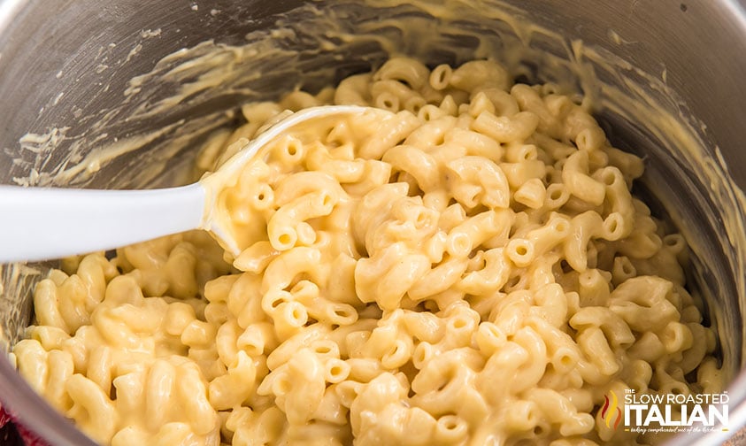 mixing cheese sauce into cooked pasta