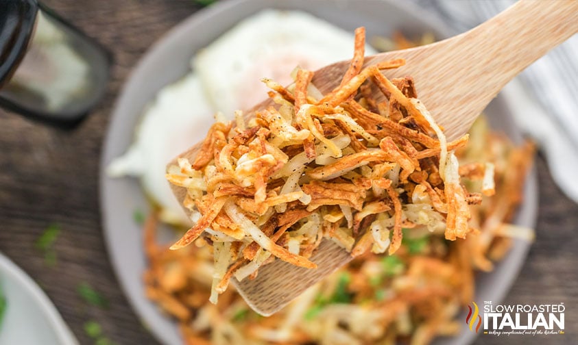 close up: crispy shredded hash browns on wooden spatula