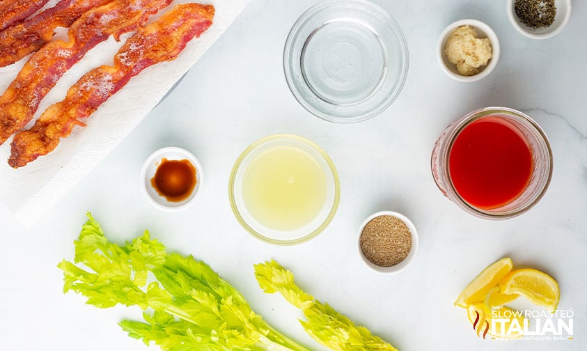 bowls of drink ingredients with bacon, celery, and lemon wedges