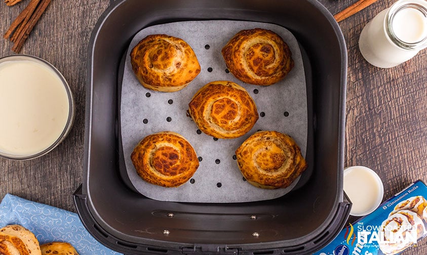 refrigerated cinnamon rolls on parchment in air fryer basket