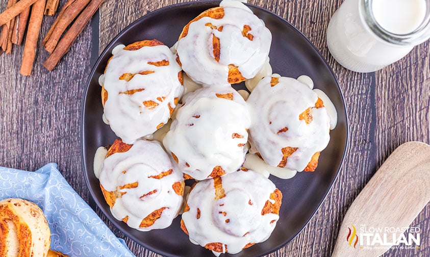 plate of cinnamon rolls covered in white frosting