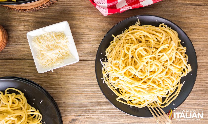 plates of cacio e pepe with dish of extra parmesan