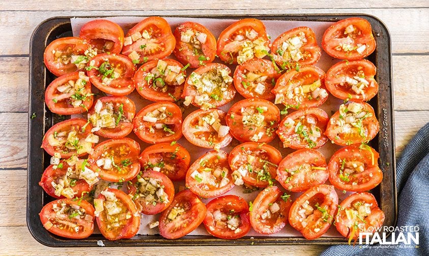 tomato halves filled with onion and garlic on baking sheet