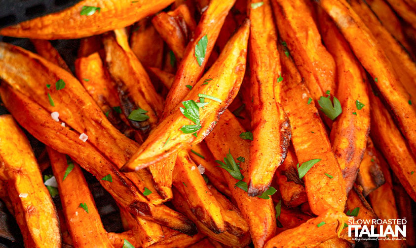 close up: crispy browned sweet potato fries with sea salt and fresh parsley
