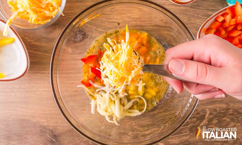 adding cheese and bell peppers to eggs