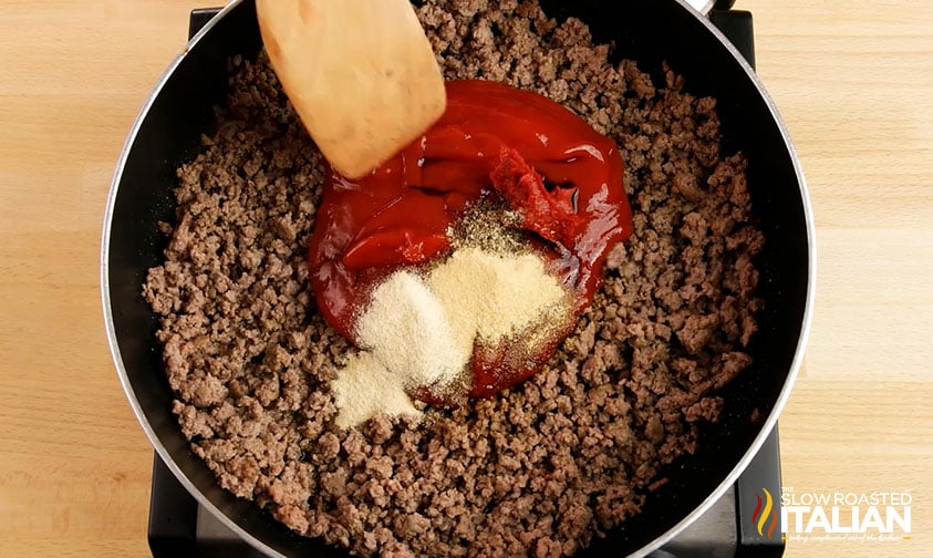 adding ketchup and seasoning to browned ground beef