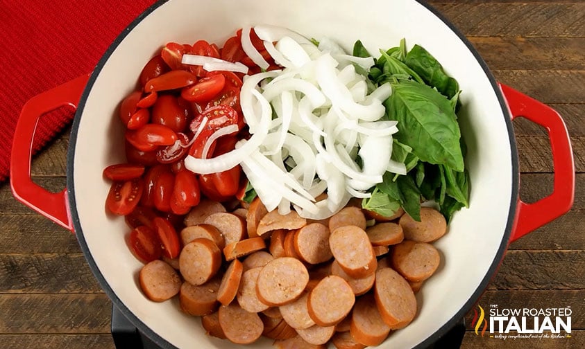sliced sausage, onion, tomatoes and spinach in a pot