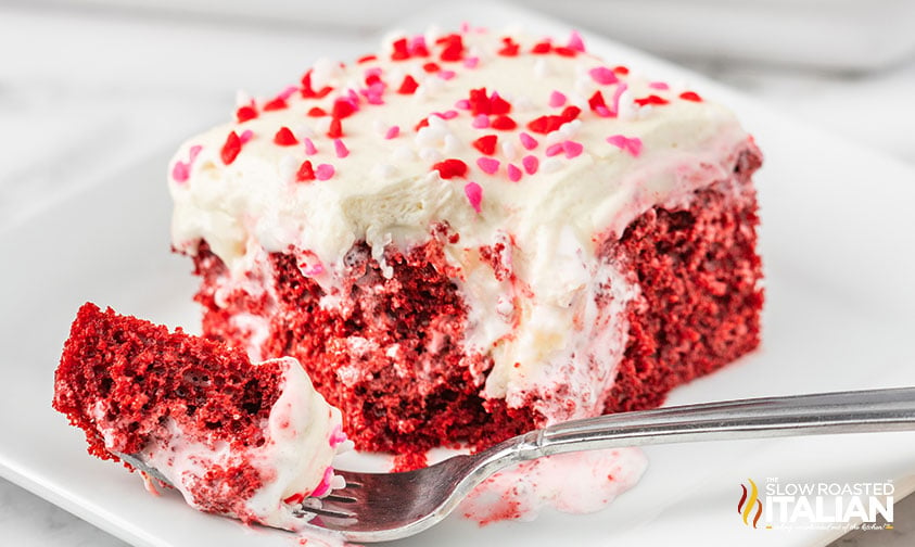 piece of red velvet poke cake on a plate with a fork
