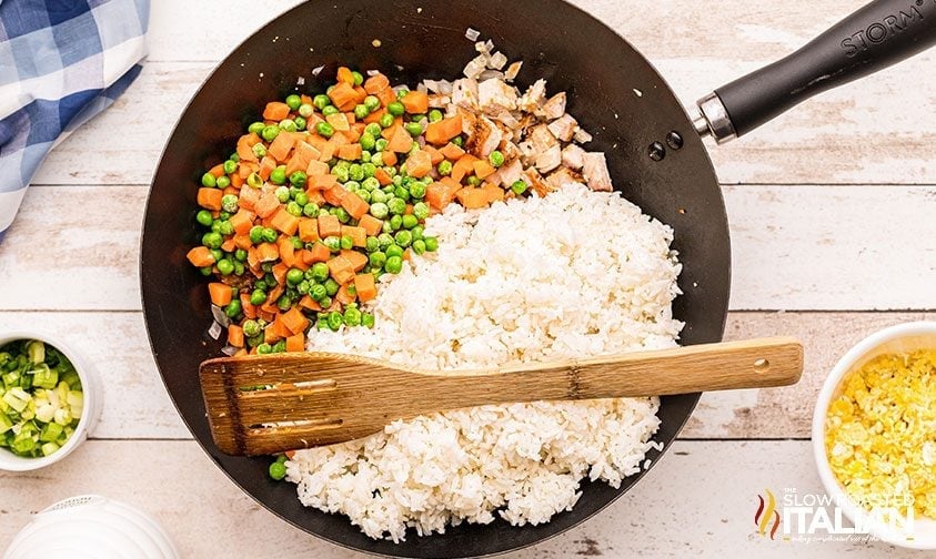 pork fried rice ingredients in wok with wooden spatula