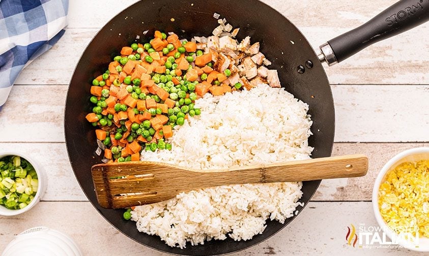 pork fried rice ingredients in wok with wooden spatula