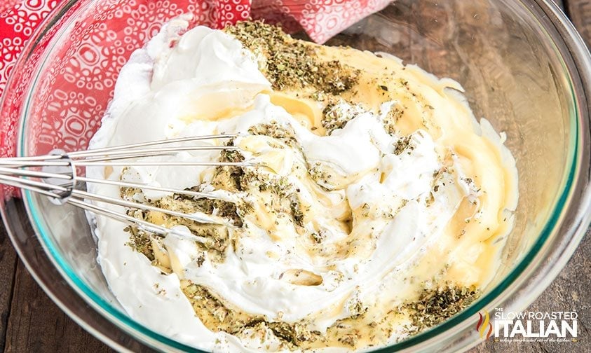 whisking sour cream and spices into cream soup in glass bowl