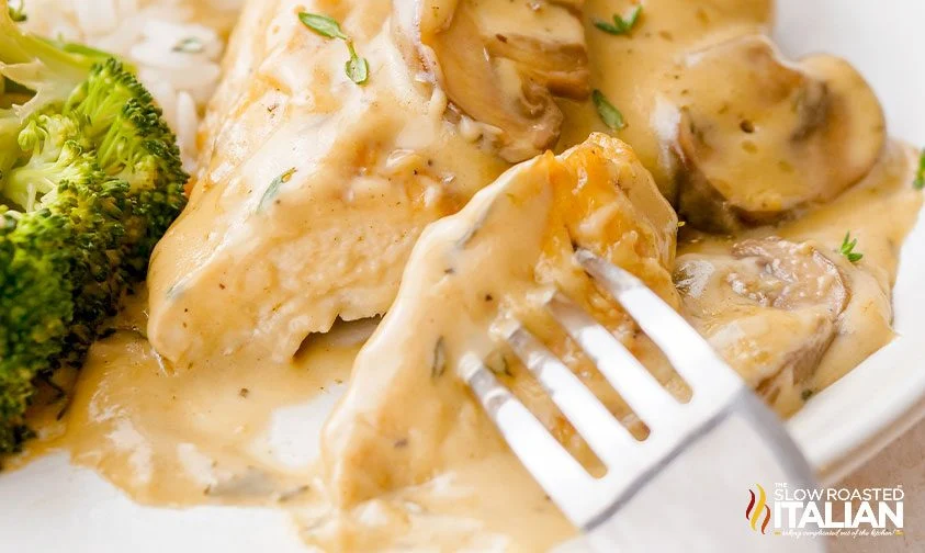 removing bite of mushroom chicken from plate with fork