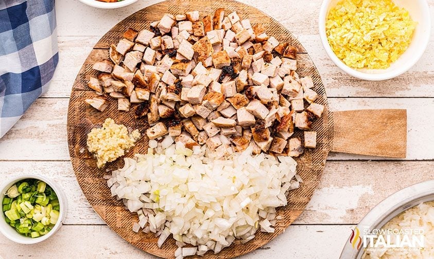 chopped pork, onion, and garlic on round wooden board