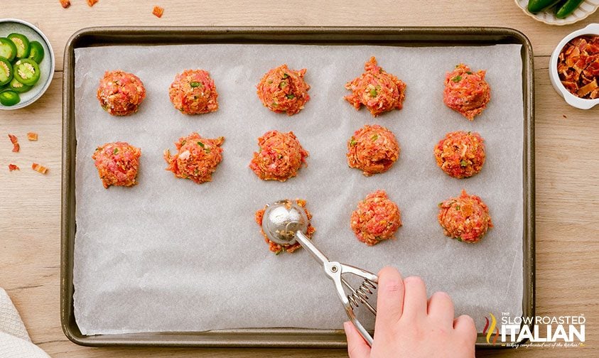 scooping meatball mixture onto parchment lined baking sheet