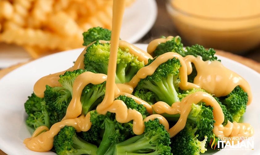drizzling cheese sauce over steamed broccoli