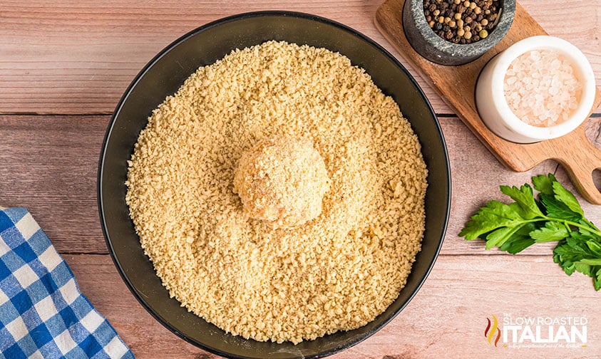 rolling mac and cheese ball in breadcrumbs