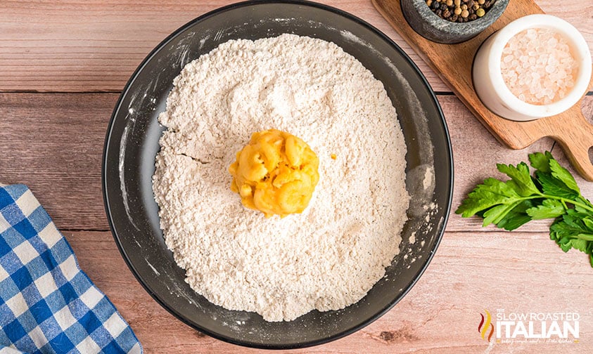 rolling frozen mac and cheese ball in flour mixture