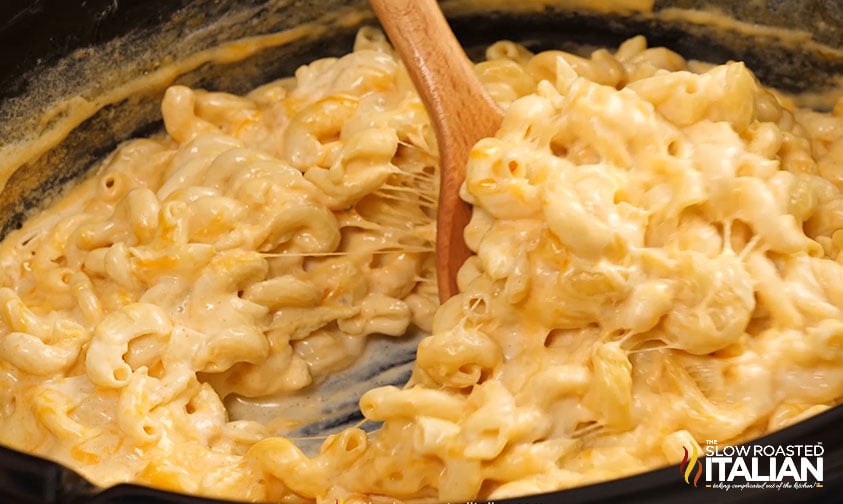 creamy mac and cheese stirred with a wooden spoon