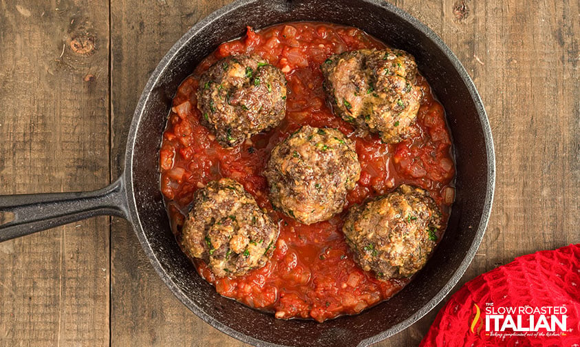 meatballs placed in skillet full of tomato sauce
