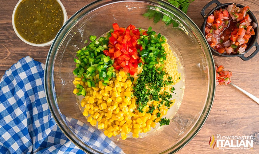 adding bell peppers, corn and spices to tamale cakes batter