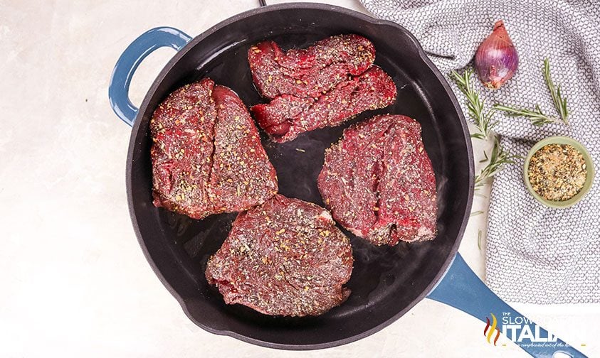 rosemary seasoned steaks in cast iron skillet