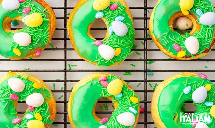 overhead: biscuit donuts on wire rack with green icing, sprinkles, and easter candies