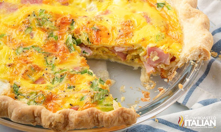 close up: cheesy ham quiche with slice removed