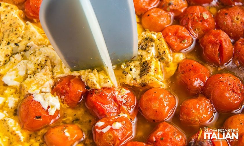 breaking up baked feta and tomatoes with meat chopper